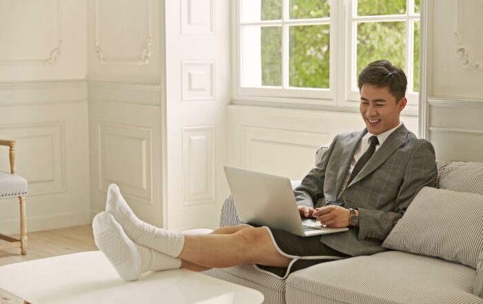 Un homme télétravaille depuis son domicile, sur son canapé, avec son ordinateur portable